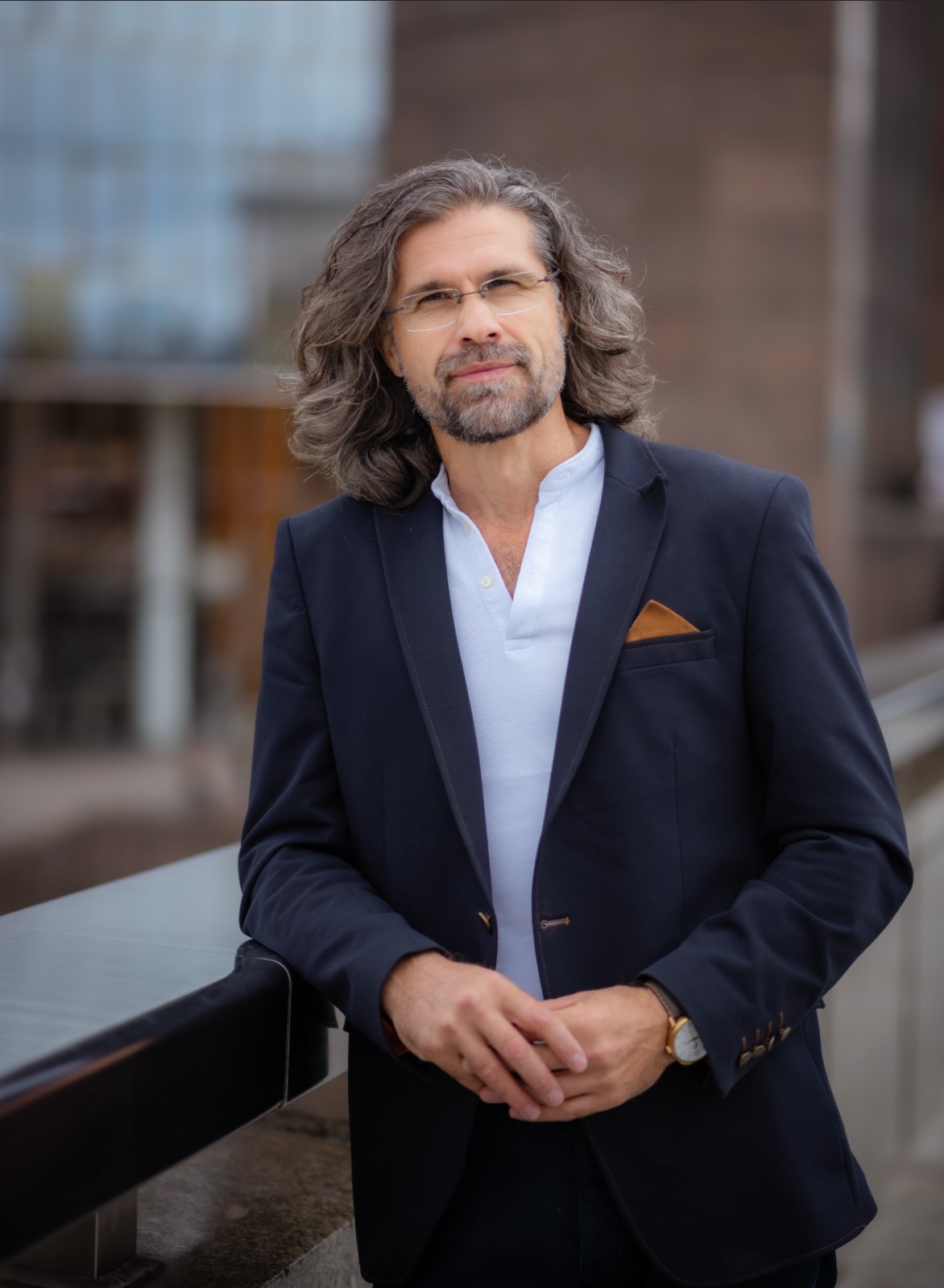 Photographer Cristian Balate dressed in his suit in front of the camera outside on the London Bridge. The background is blurred to isolate the subject from the environment.