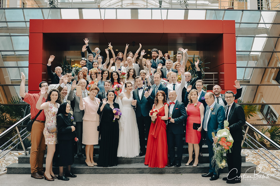 The bride and groom on their wedding day after the civil marriage was celebrated. They are surrounded by the closest friends, relatives, parents and godparents who are seated closed to each other for the final group photo.