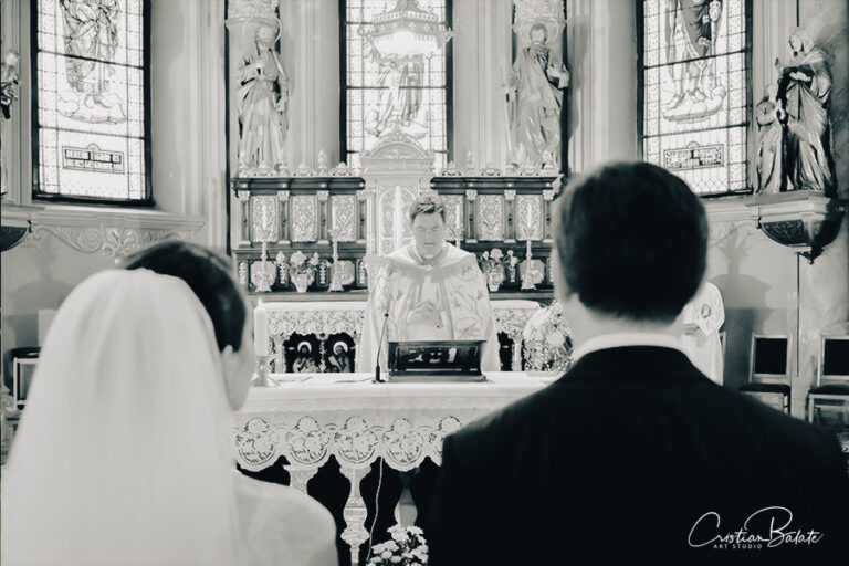 Wedding day photography with the bride and groom seen from behind and the Christian priest officiating the religious service