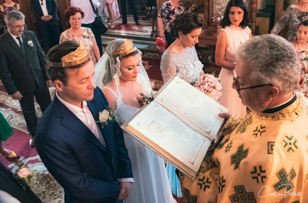 Top view of the moment when the priest is reading from the holy book for the bride and groom who are deeply experiencing the spiritual and emotional vibe of the environment. The married couple are surrounded by the parents and friends whoa re happy on this wedding day.